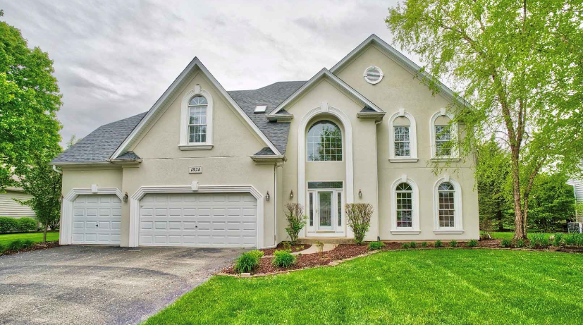 A large house with two garages and a lush green lawn.