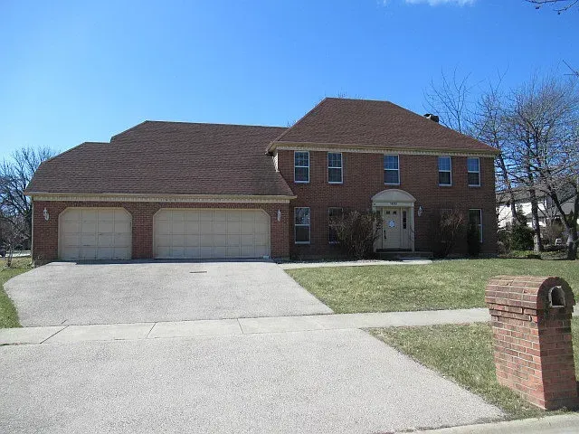 A large house with two garages and a lush green lawn.