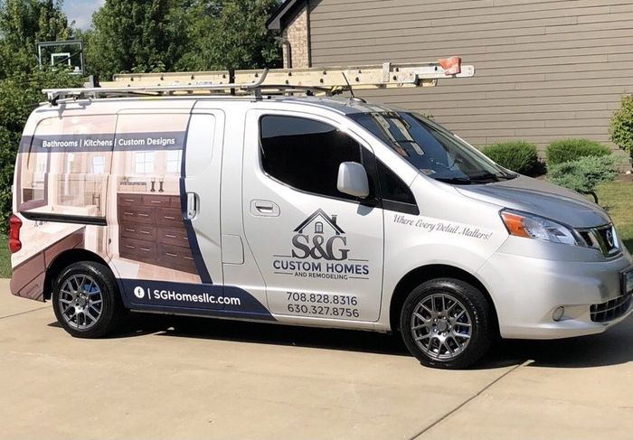 A white van with a ladder on top of it is parked in front of a house.