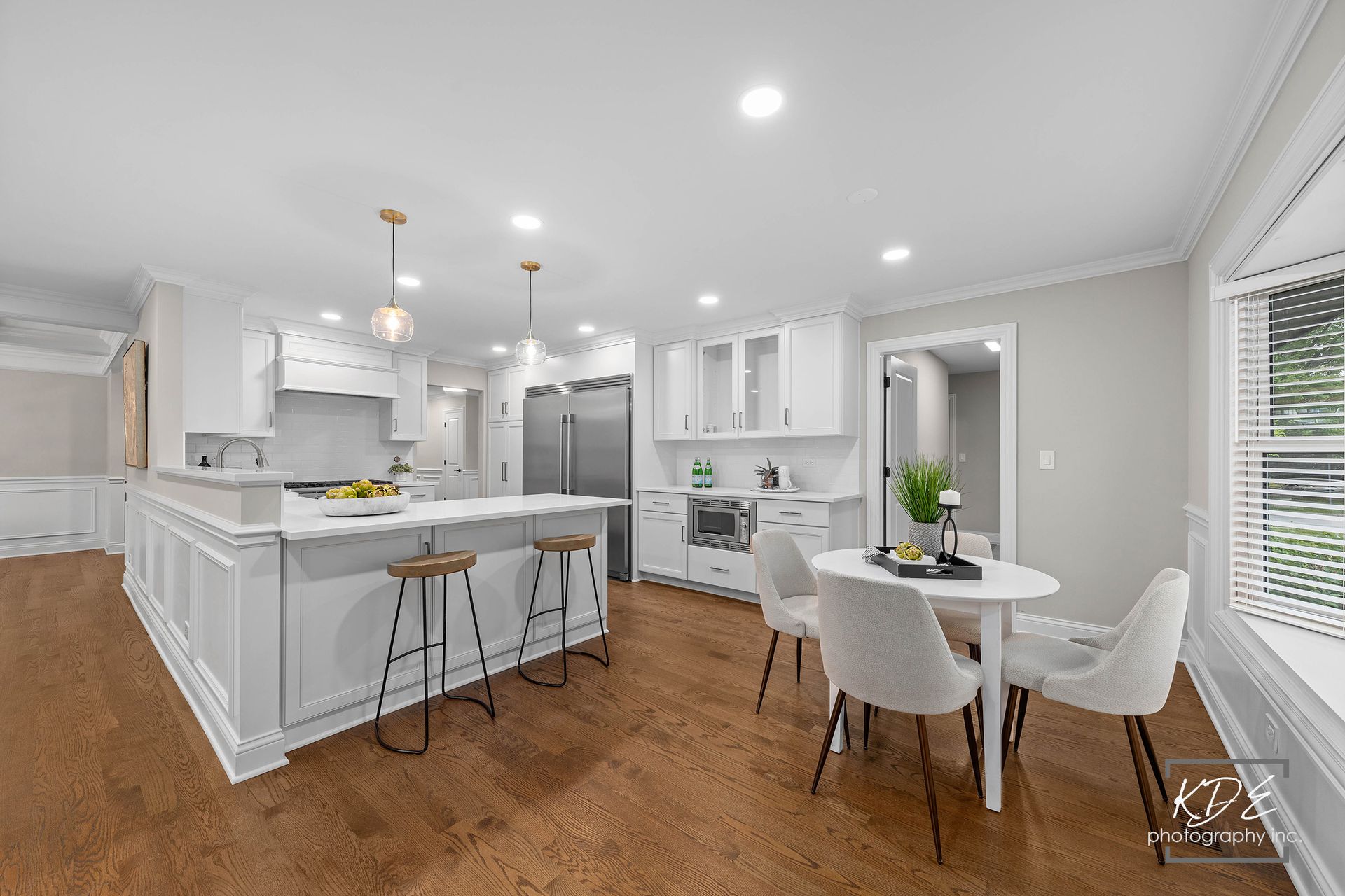 A kitchen and dining room in a house with hardwood floors and white cabinets.
