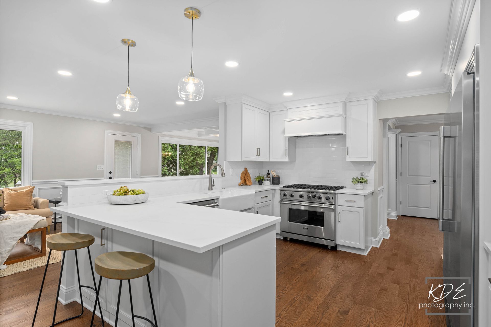 A kitchen with white cabinets , stainless steel appliances , hardwood floors and a large island.