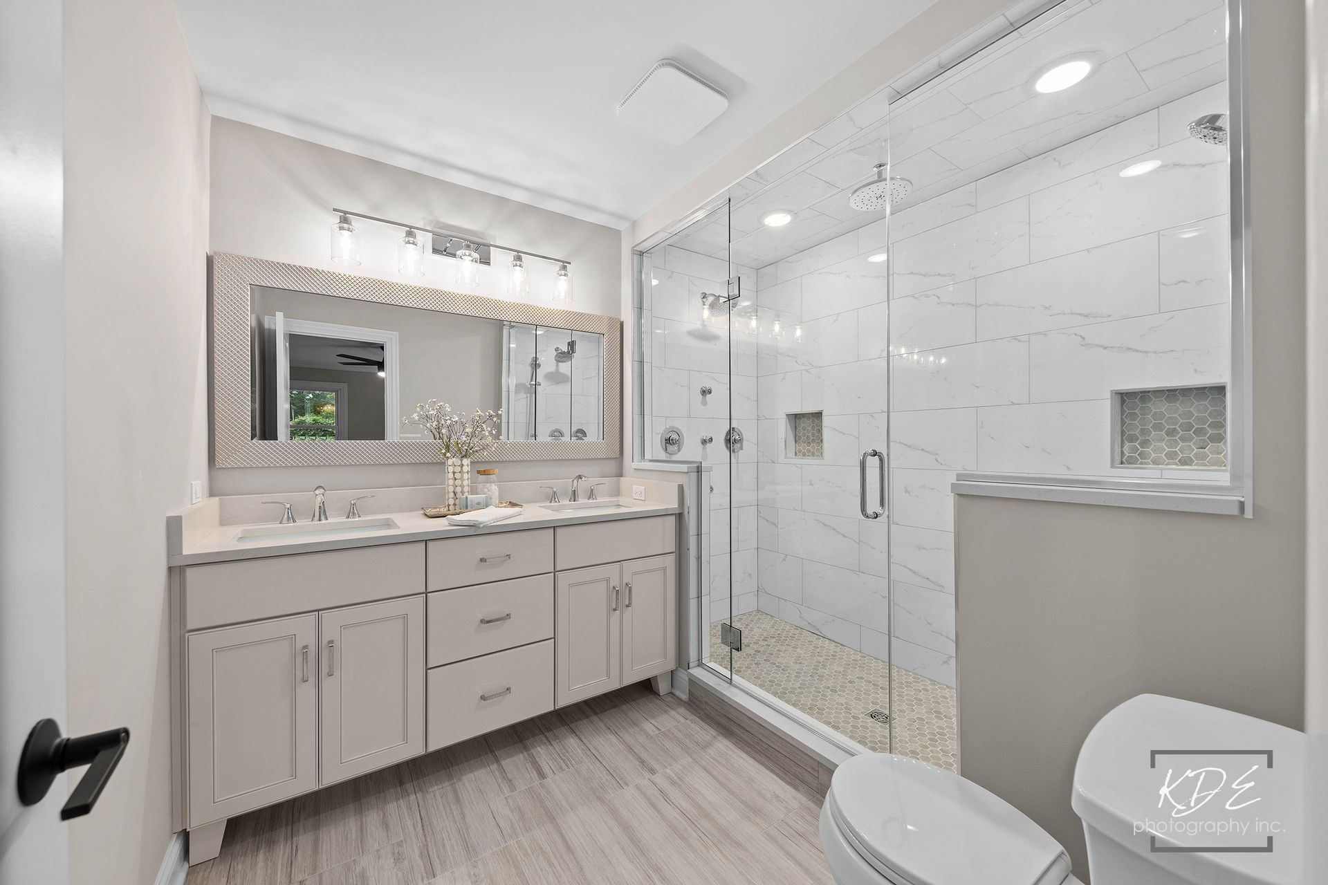 A bathroom with two sinks , a toilet , and a walk in shower.