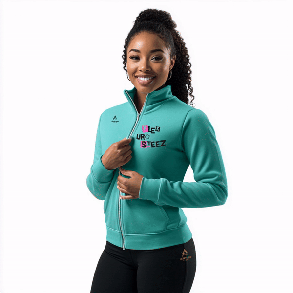 Woman in teal zip-up jacket with text, black leggings; smiling against white backdrop.