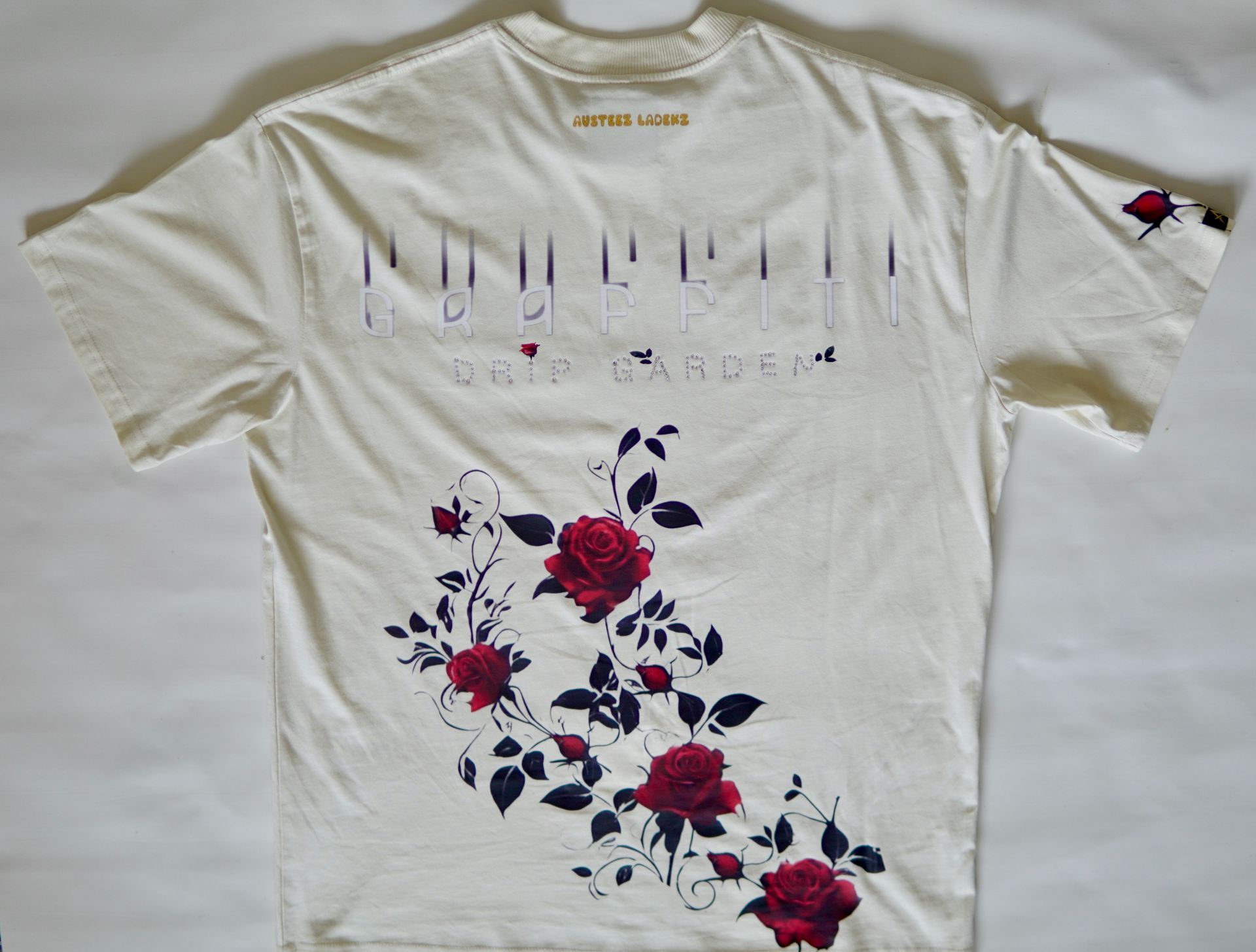 Off-white t-shirt with floral print. Dark red roses and text design, including 