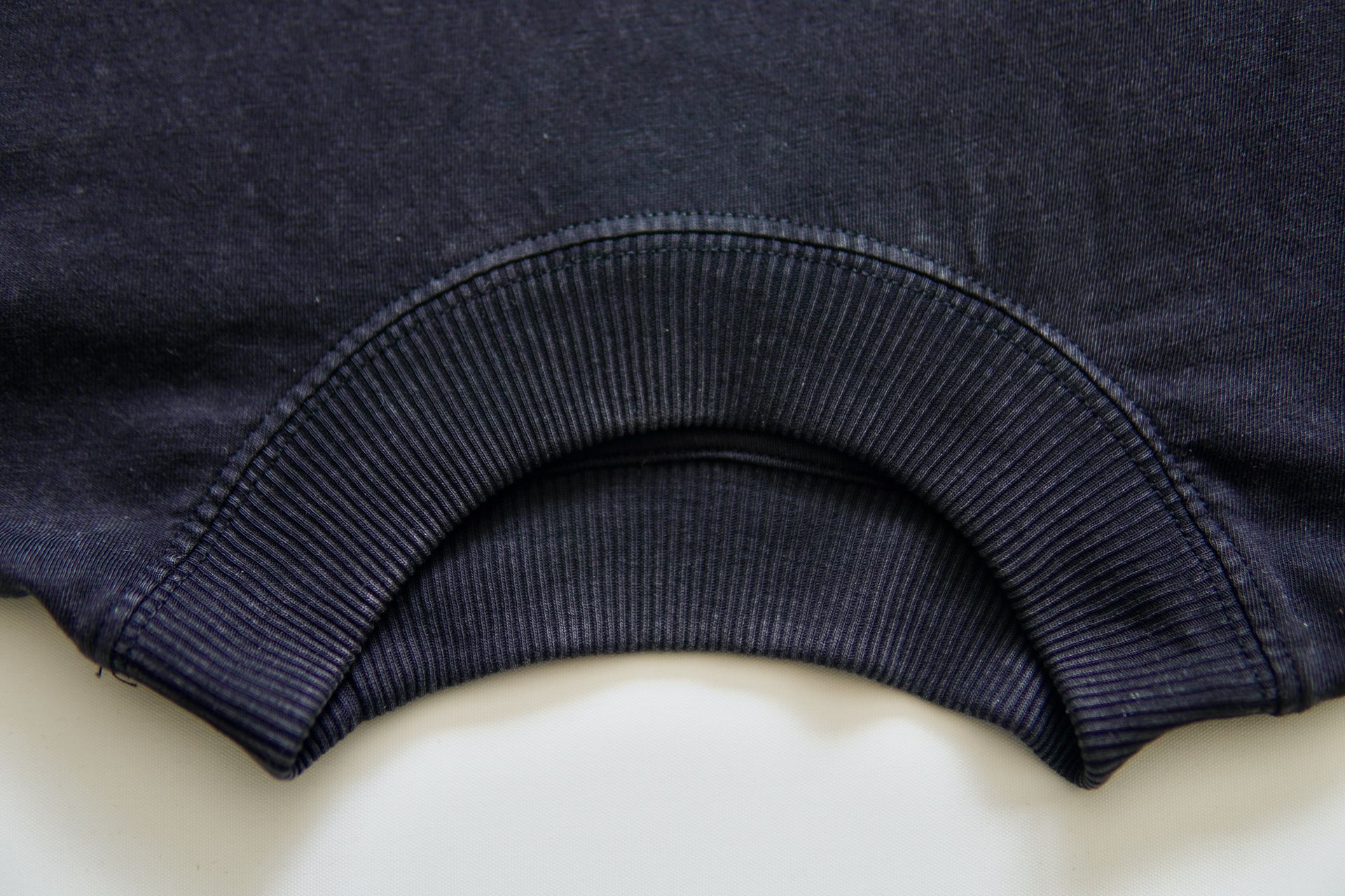 Close-up of a navy blue ribbed crew neck collar on a dark blue sweatshirt.