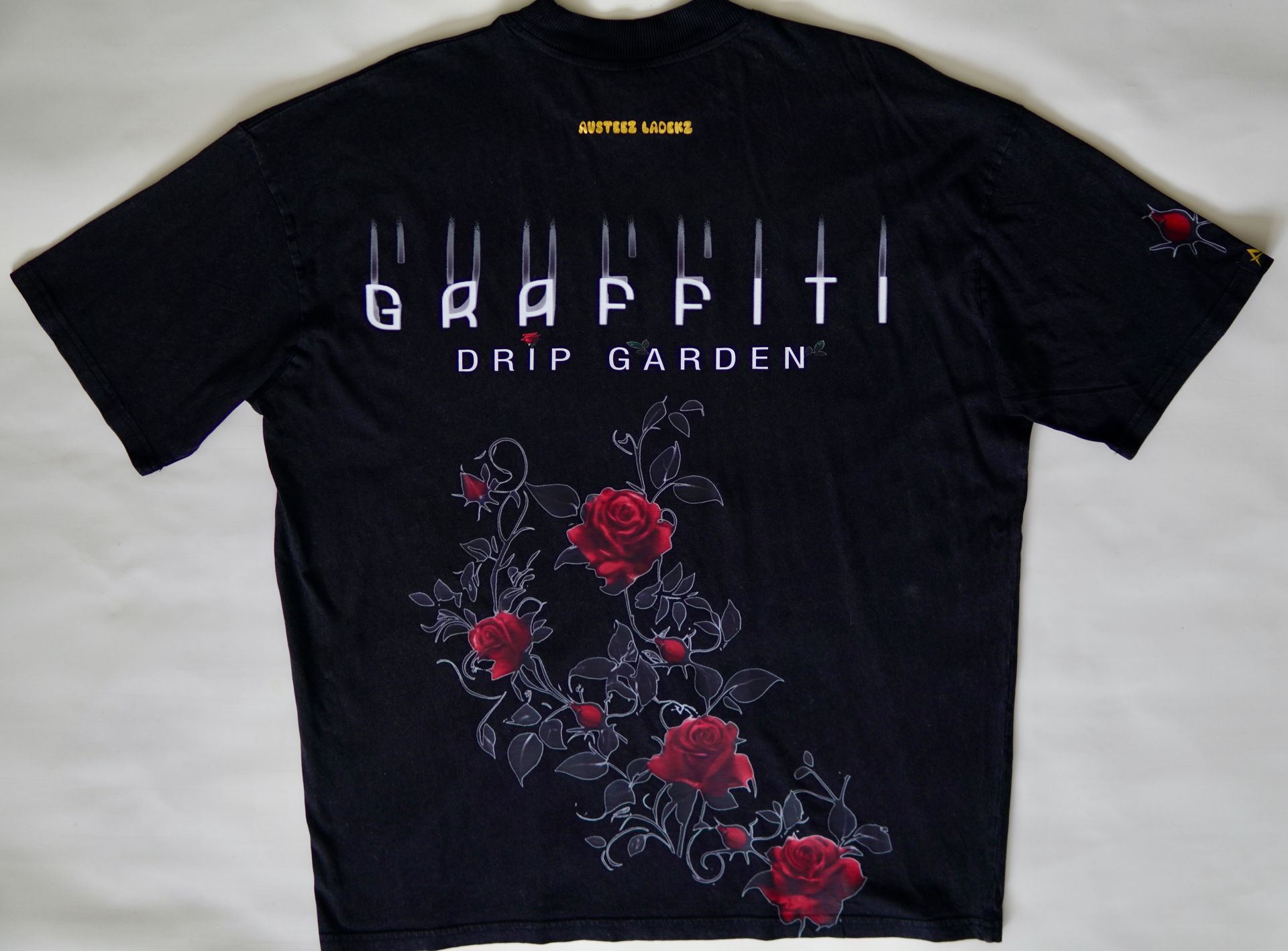 Black t-shirt with graffiti-style text and red rose graphic on the back.