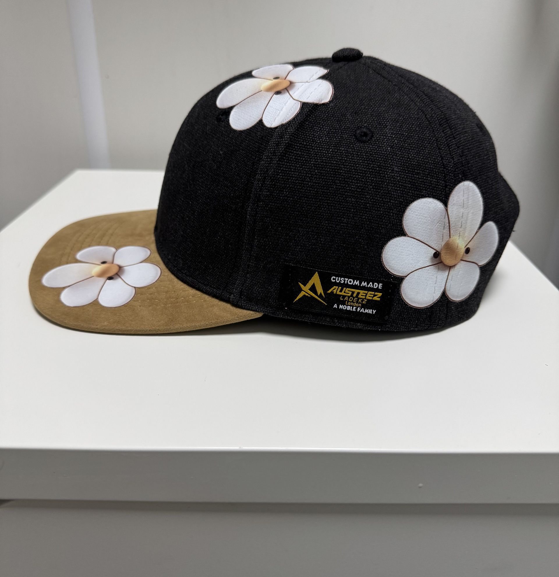 Black hat with daisy design on brim and crown. Tan brim.