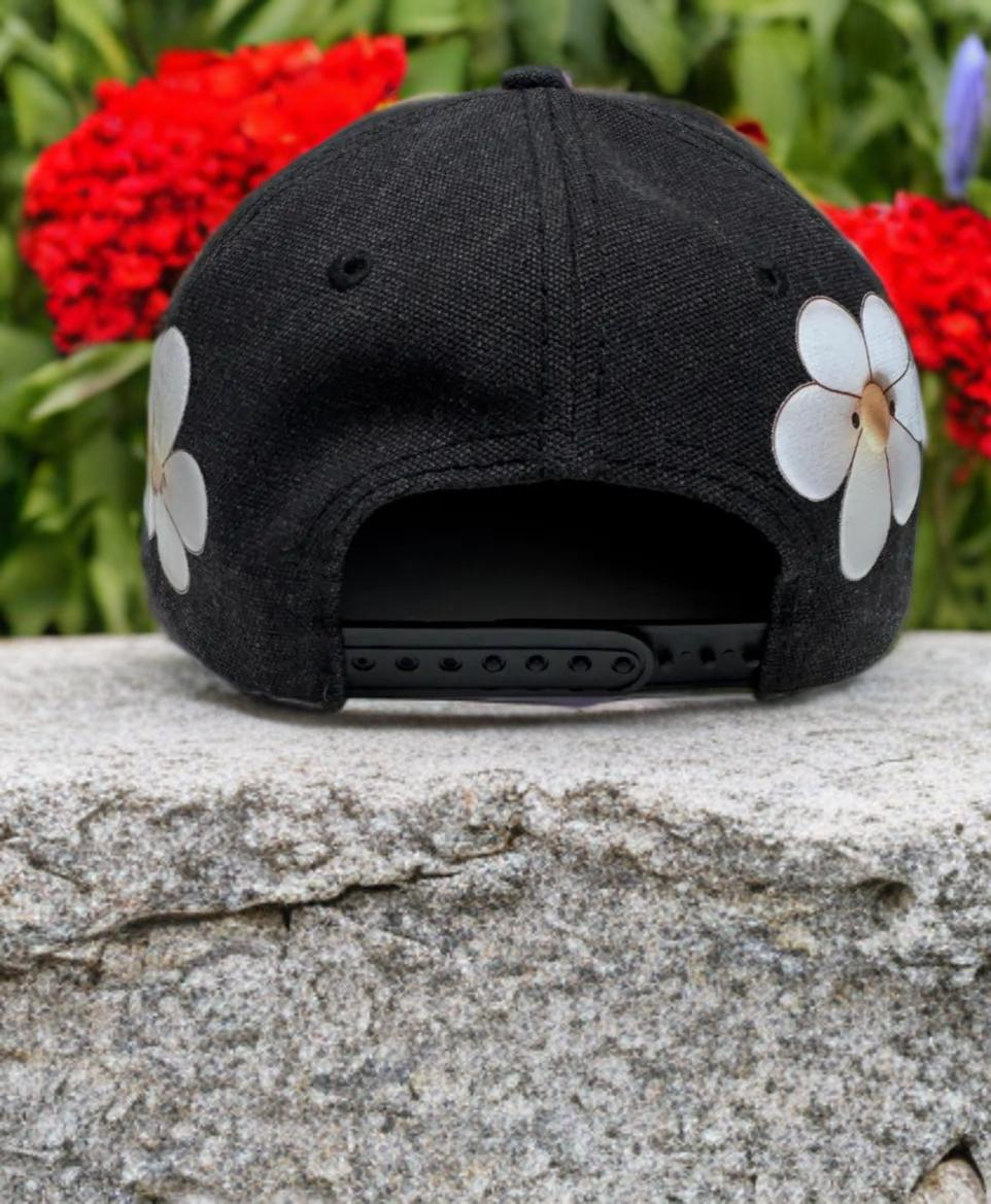 Black hat with daisy design on brim and crown. Tan brim.