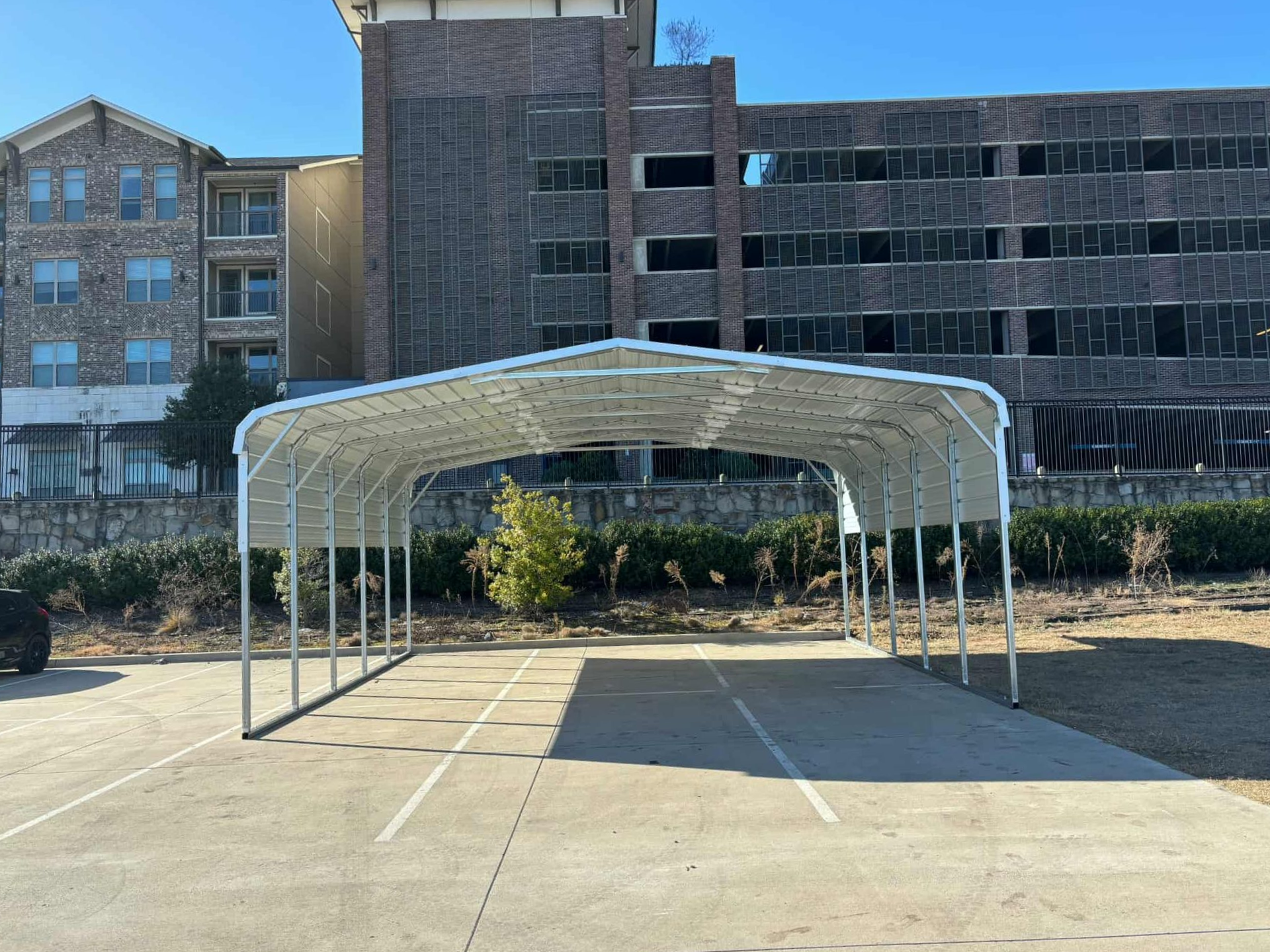 Empty white canopy tent in a parking lot with a brick building in the background