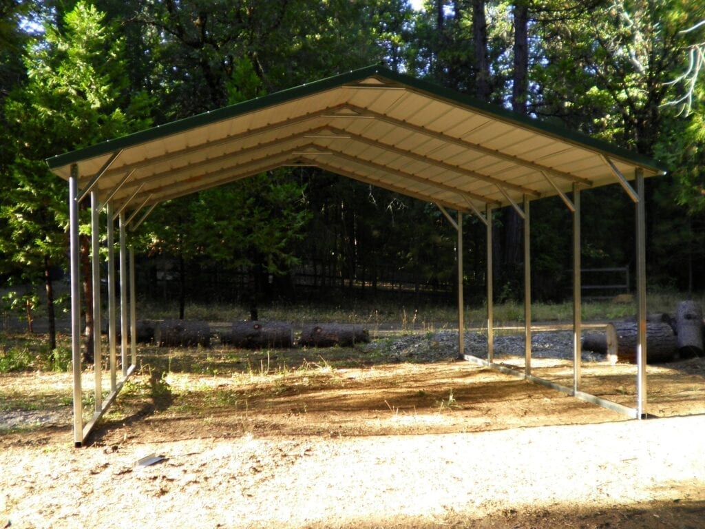 Metal carport canopy with a tan roof in a wooded outdoor area