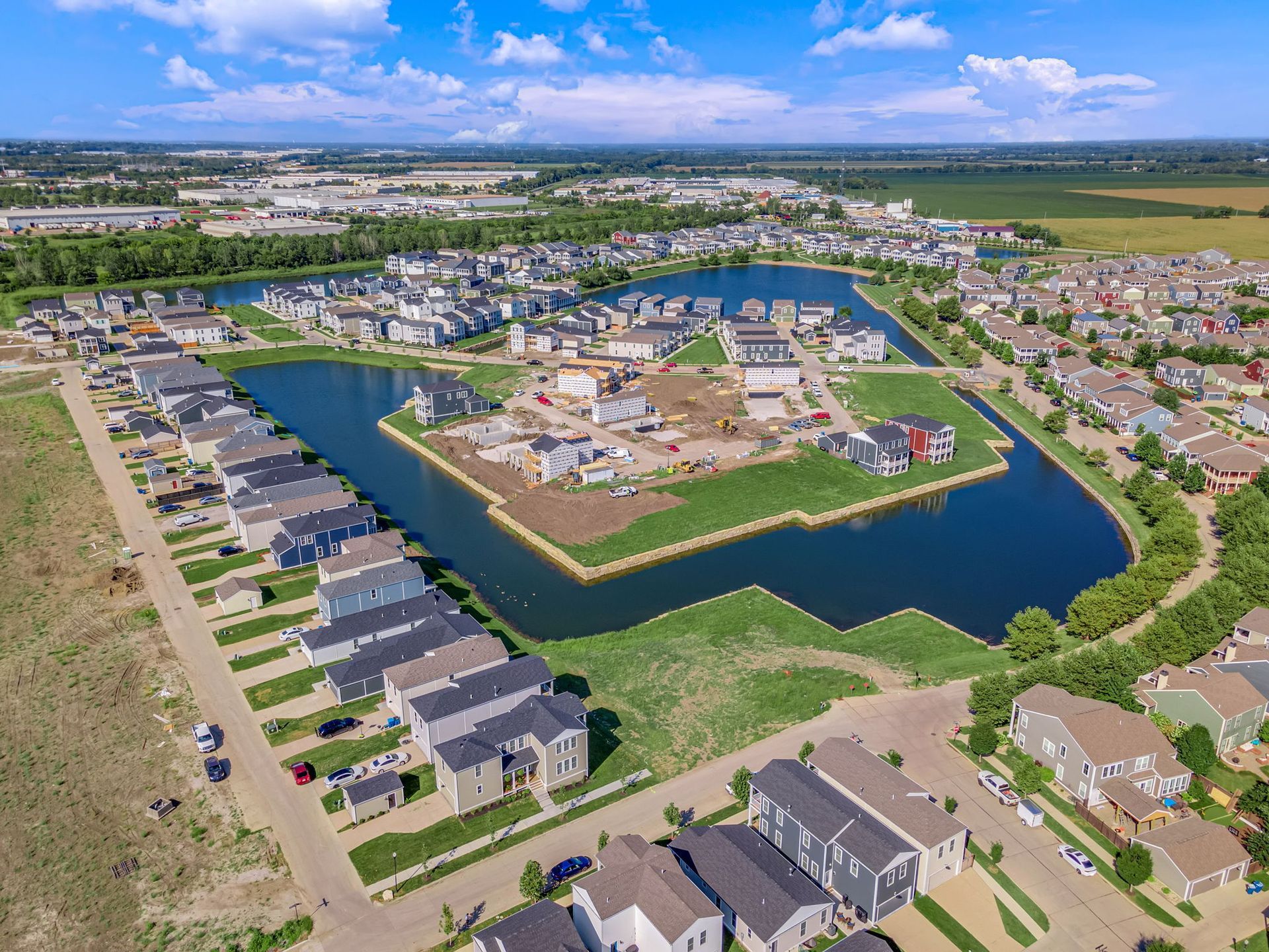 Aerial view of a suburban neighborhood with a central construction site surrounded by homes and water channels.