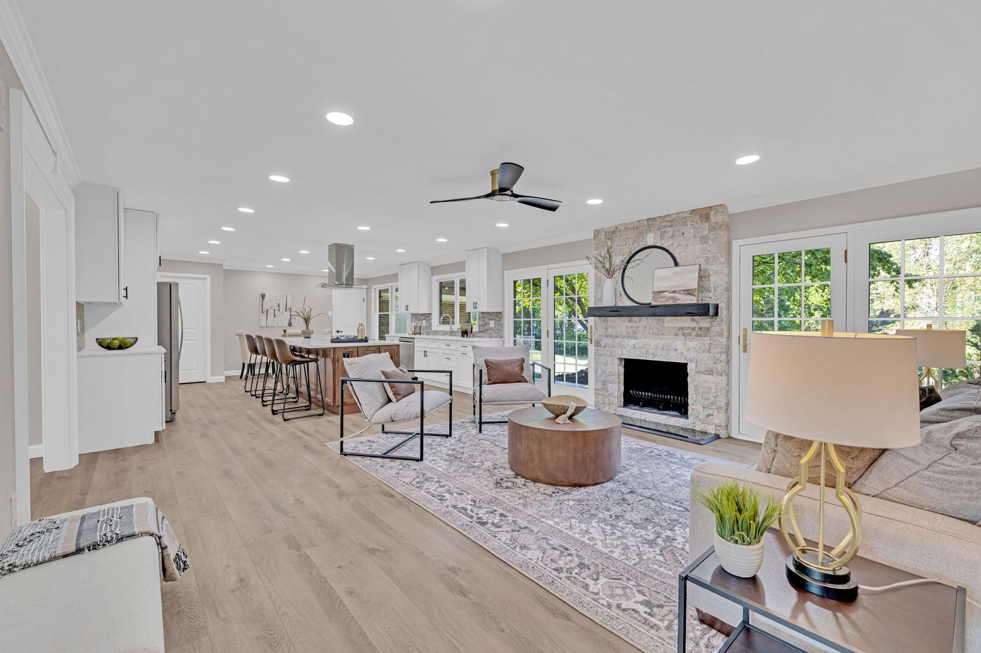 Bright open-concept living room with fireplace, seating area, dining table, and large windows