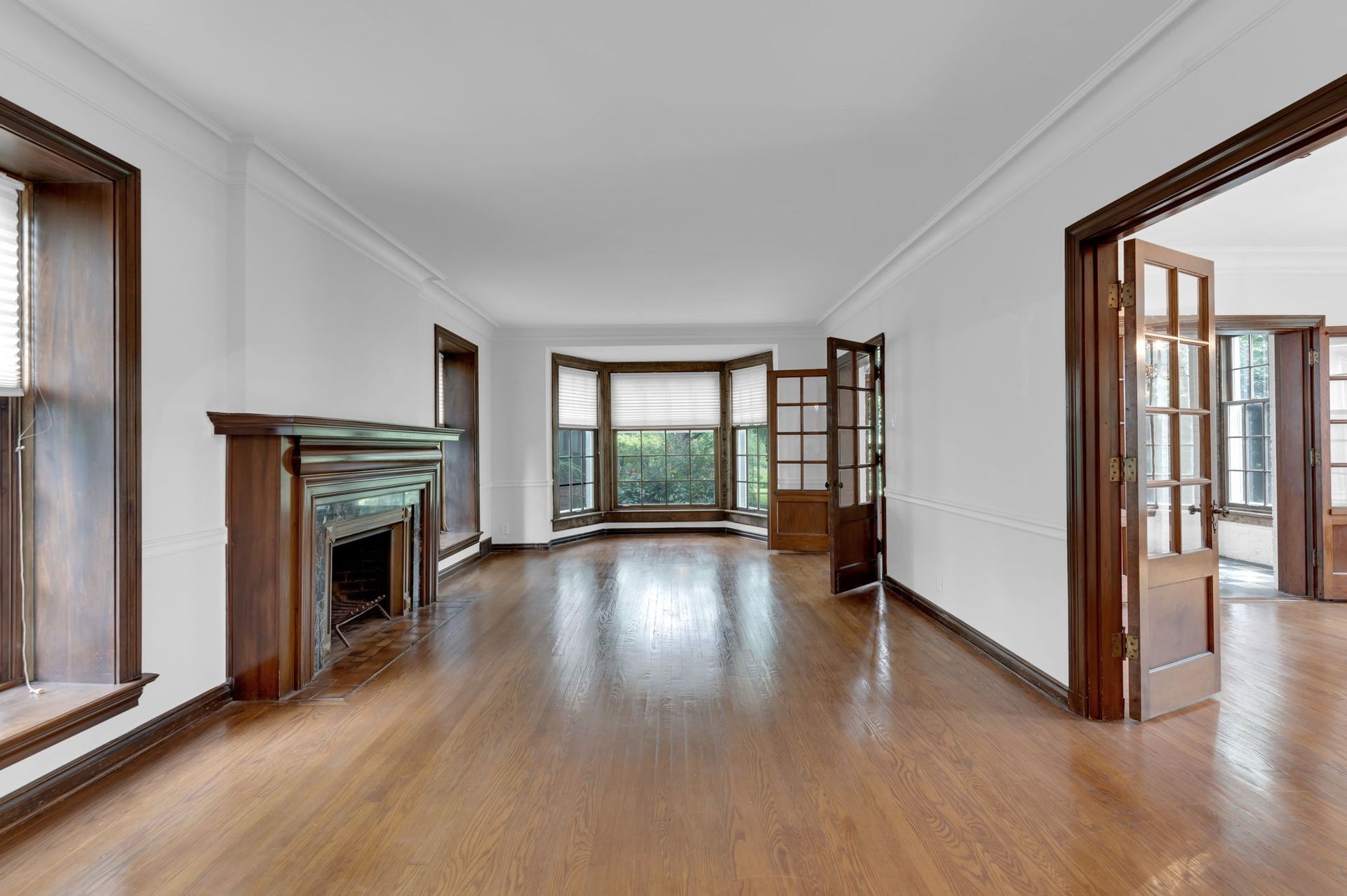 Empty living room with hardwood floors, fireplace, and large windows