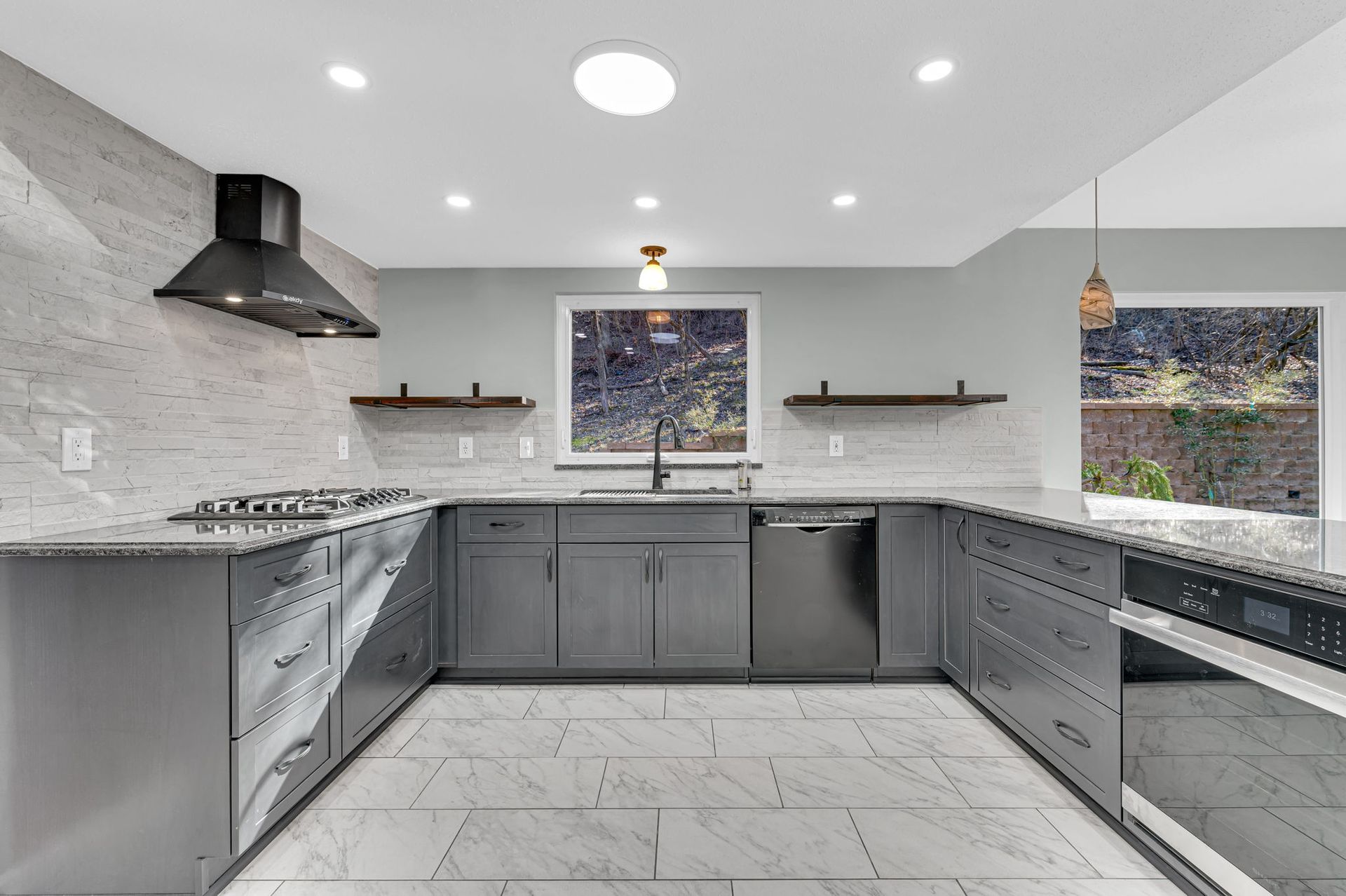 Modern gray kitchen with stainless steel appliances, white tile floor, and recessed ceiling lights