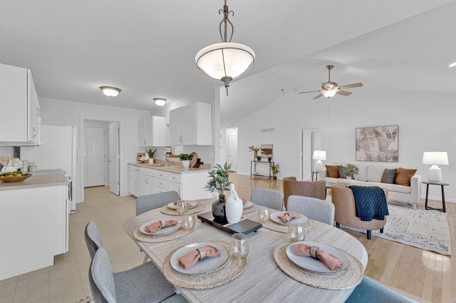 Bright open dining and living area with white furniture, blue accents, and a table set for two.