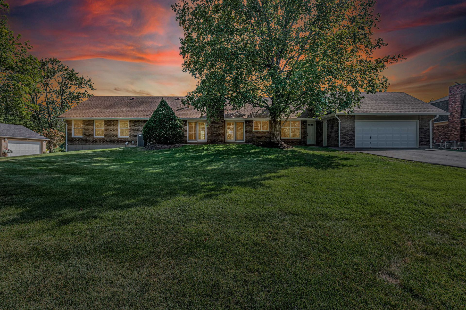 Single-story suburban house with a large green lawn at sunset