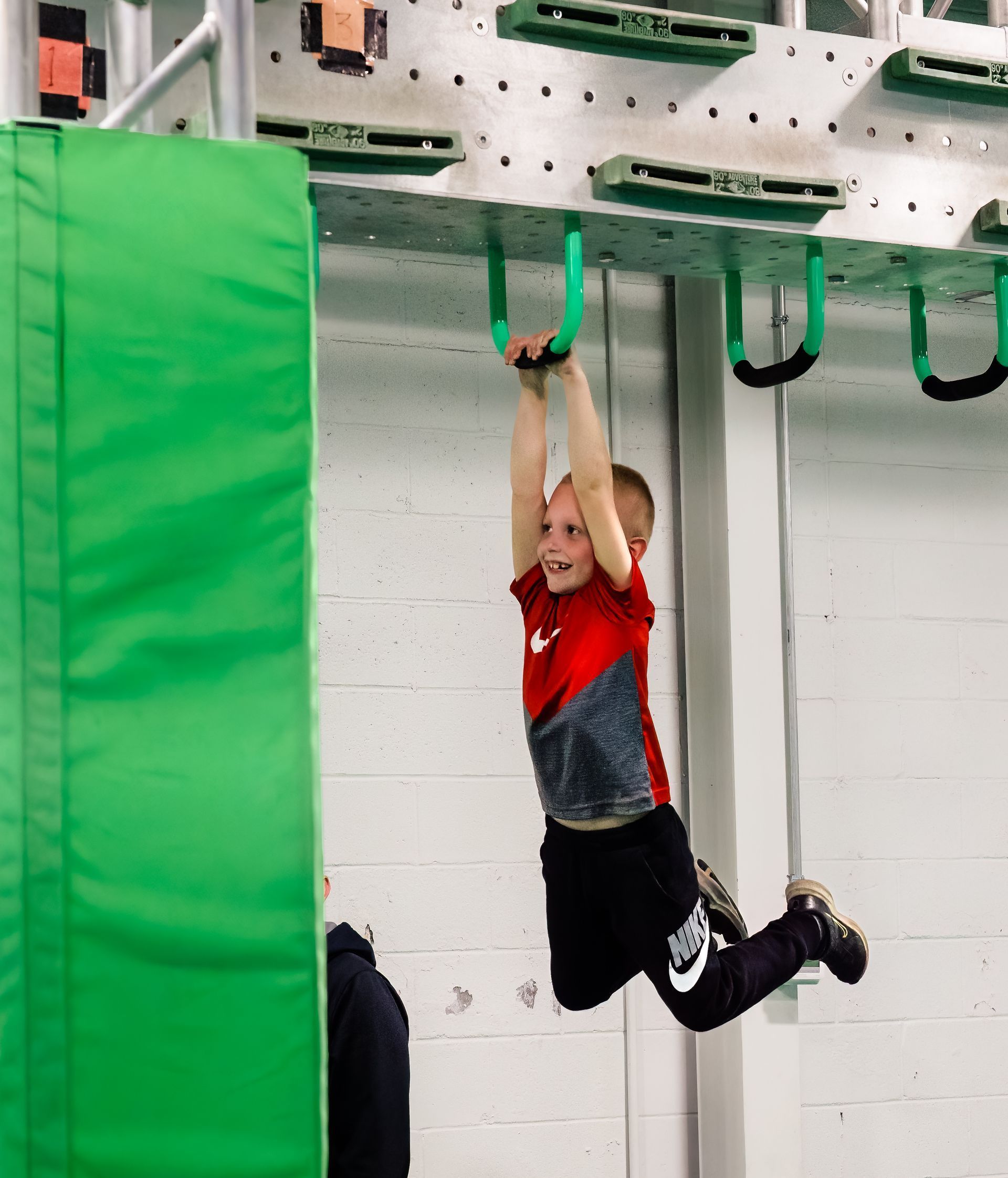 Child hanging from rings on ninja obstacle course training