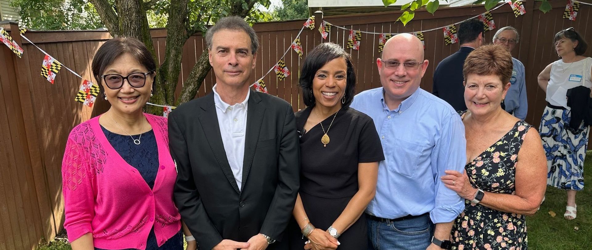 Delegate Fraser-Hidalgo outdoors in a backyard, standing together in front of a wooden fence and greenery
