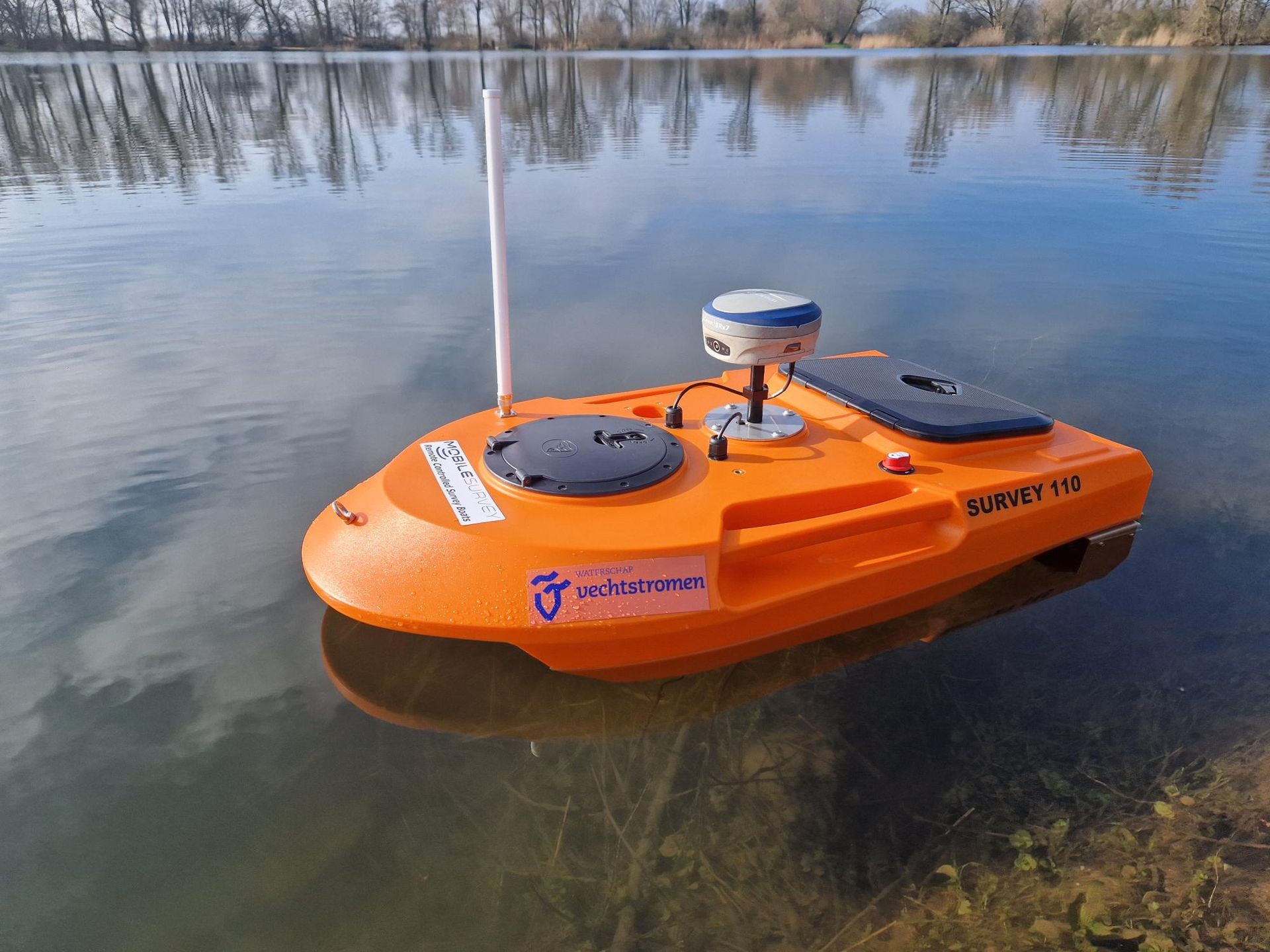 Een klein oranje bootje drijft op een meer.