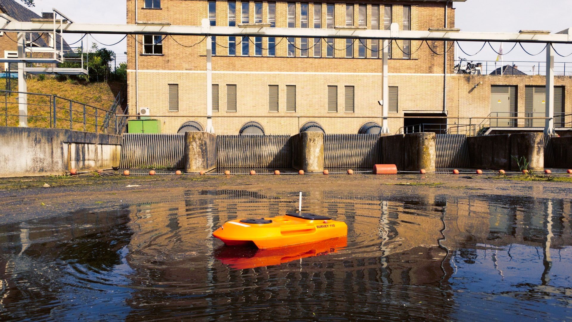 Een gele boot drijft in het water voor een gebouw