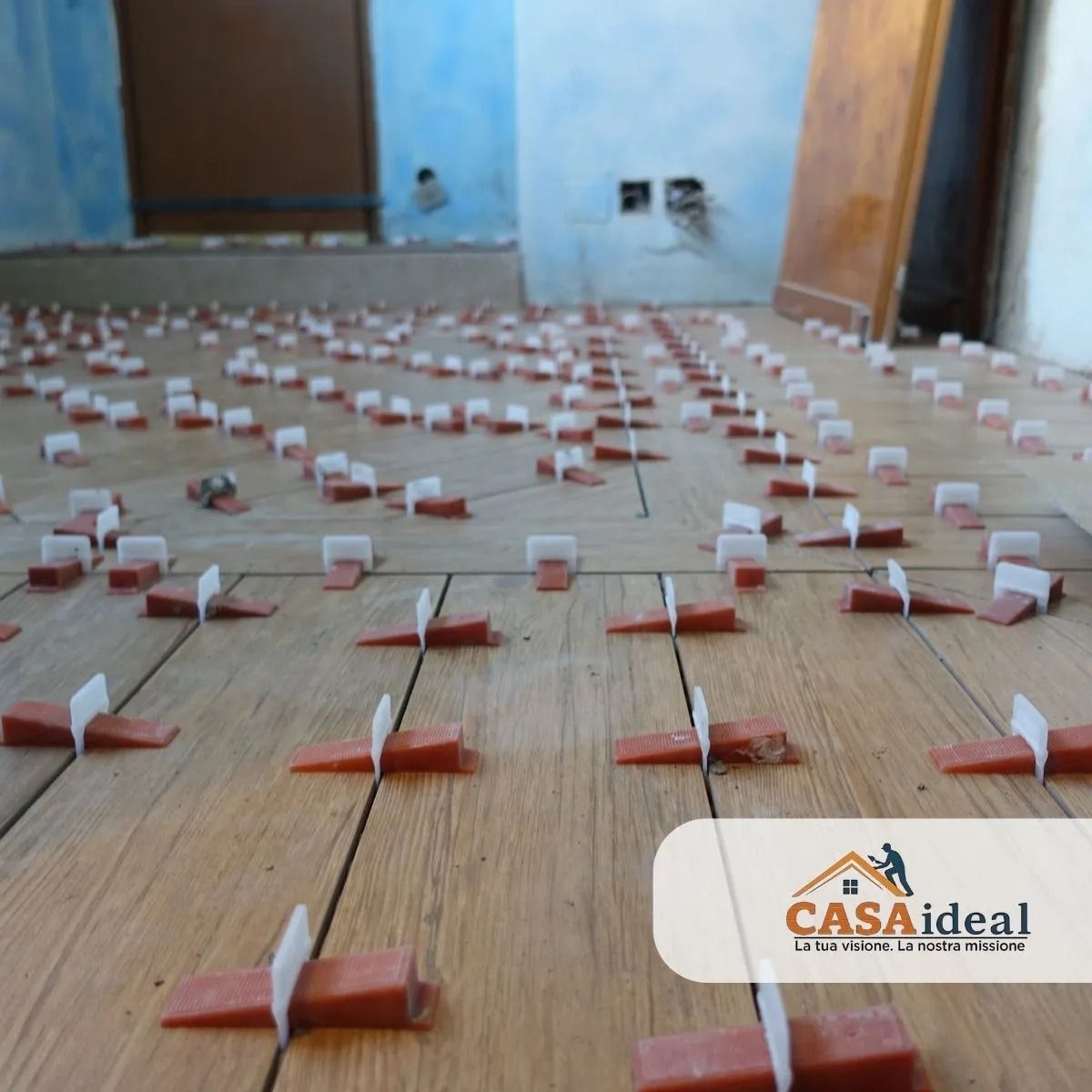 File di distanziatori per piastrelle rosse e bianche disposte su un pavimento di legno in una stanza
