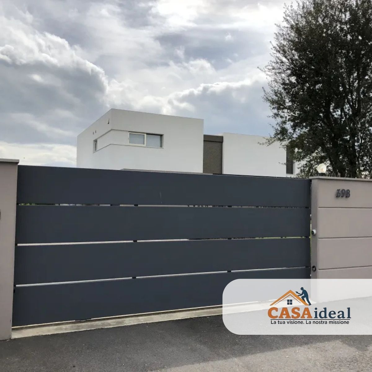 Casa moderna bianca dietro un cancello grigio scuro sotto un cielo nuvoloso