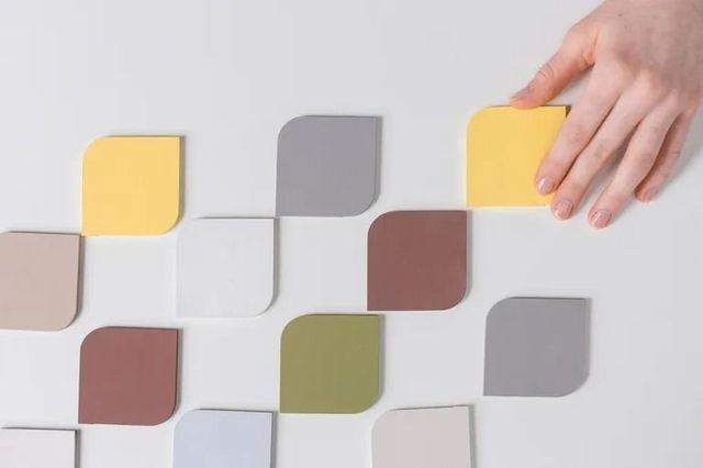 Mano che posiziona una tessera gialla tra una griglia di tessere quadrate colorate su uno sfondo chiaro