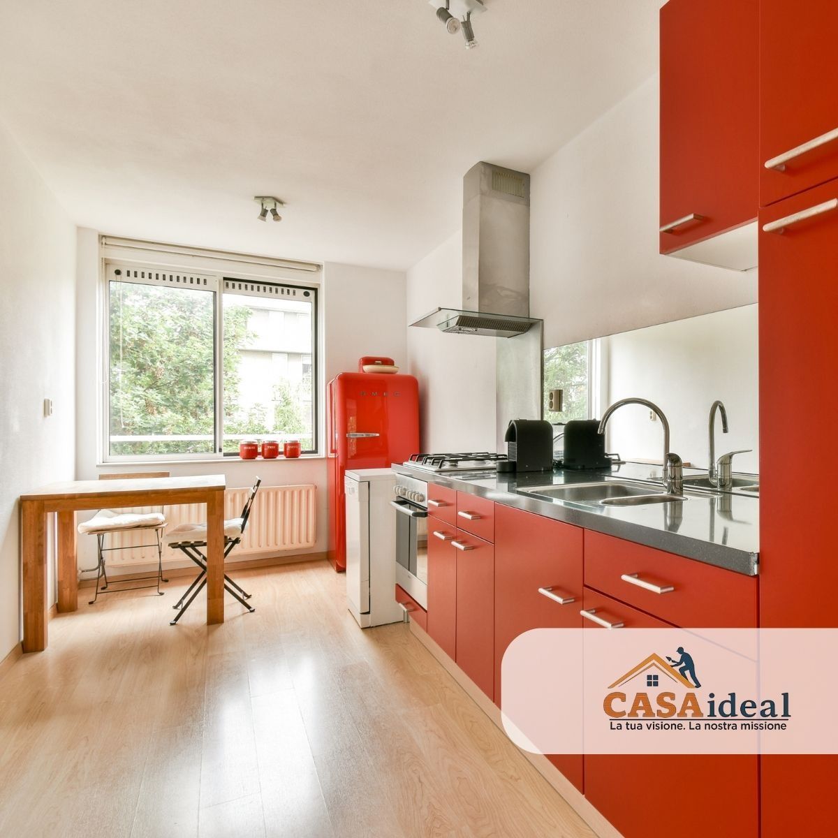 Cucina moderna con mobili rossi, elettrodomestici in acciaio inossidabile e un piccolo tavolo da pranzo accanto 