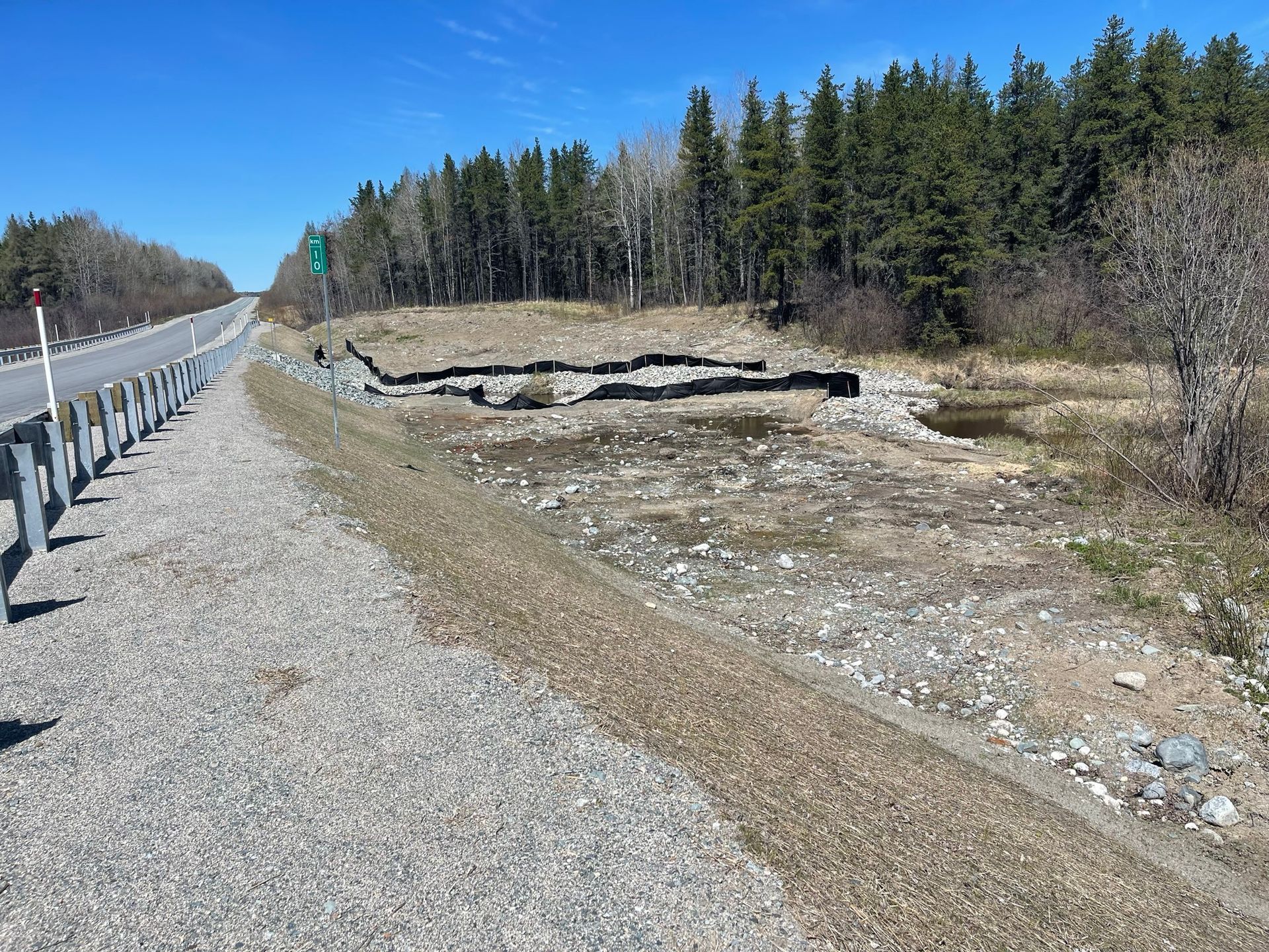 Un chemin de gravier avec une clôture et des arbres sur le côté.
