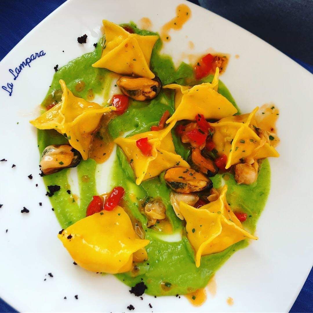 Un piatto bianco con una salsa verde e triangoli gialli sopra