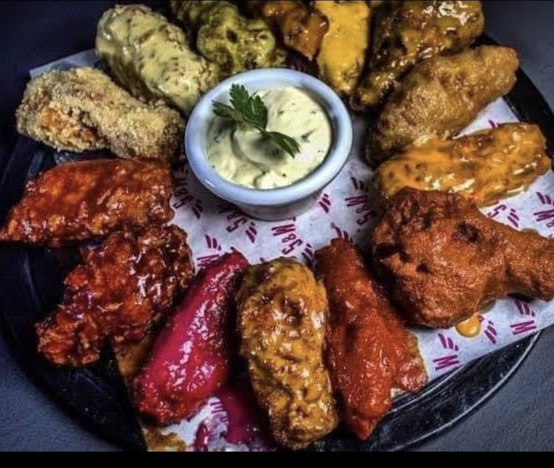 Un vassoio di ali di pollo con una ciotola di salsa di accompagnamento