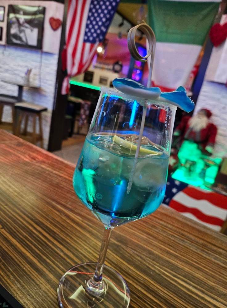 Un drink blu in un bicchiere da vino su un bancone del bar.