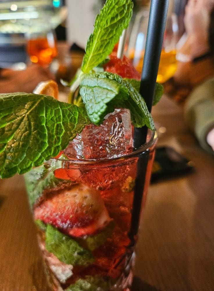 Un primo piano di un drink con fragole e menta su un tavolo.