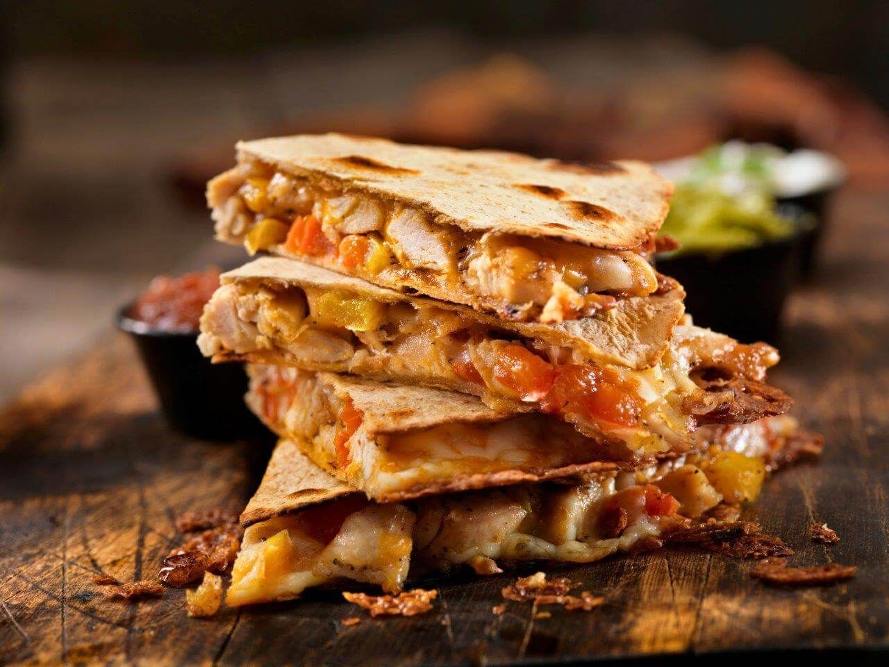 Una quesadilla è impilata una sopra l'altra su un tavolo di legno.