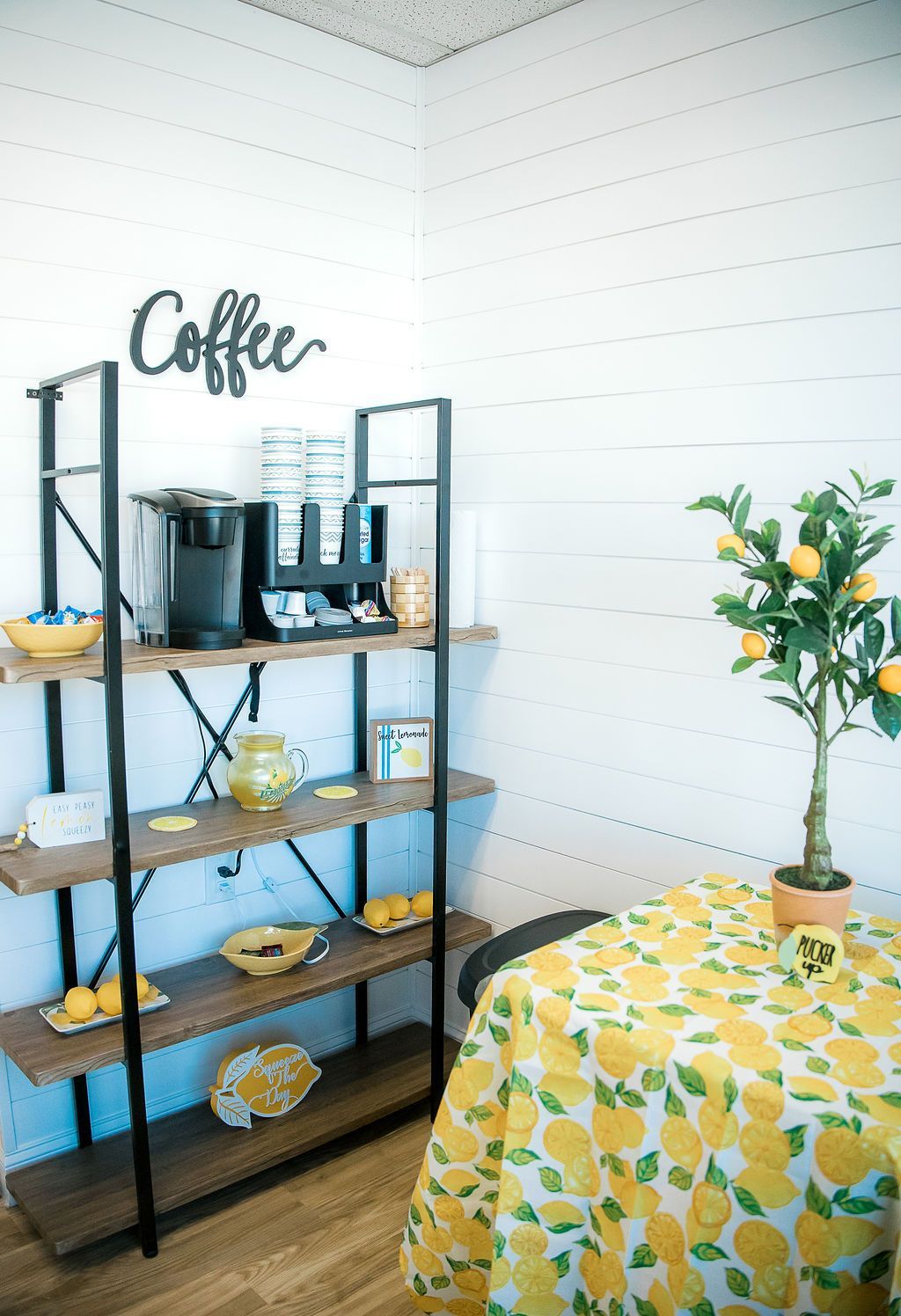 A room with a table , shelves , and a coffee machine for the parents at the indoor playground.