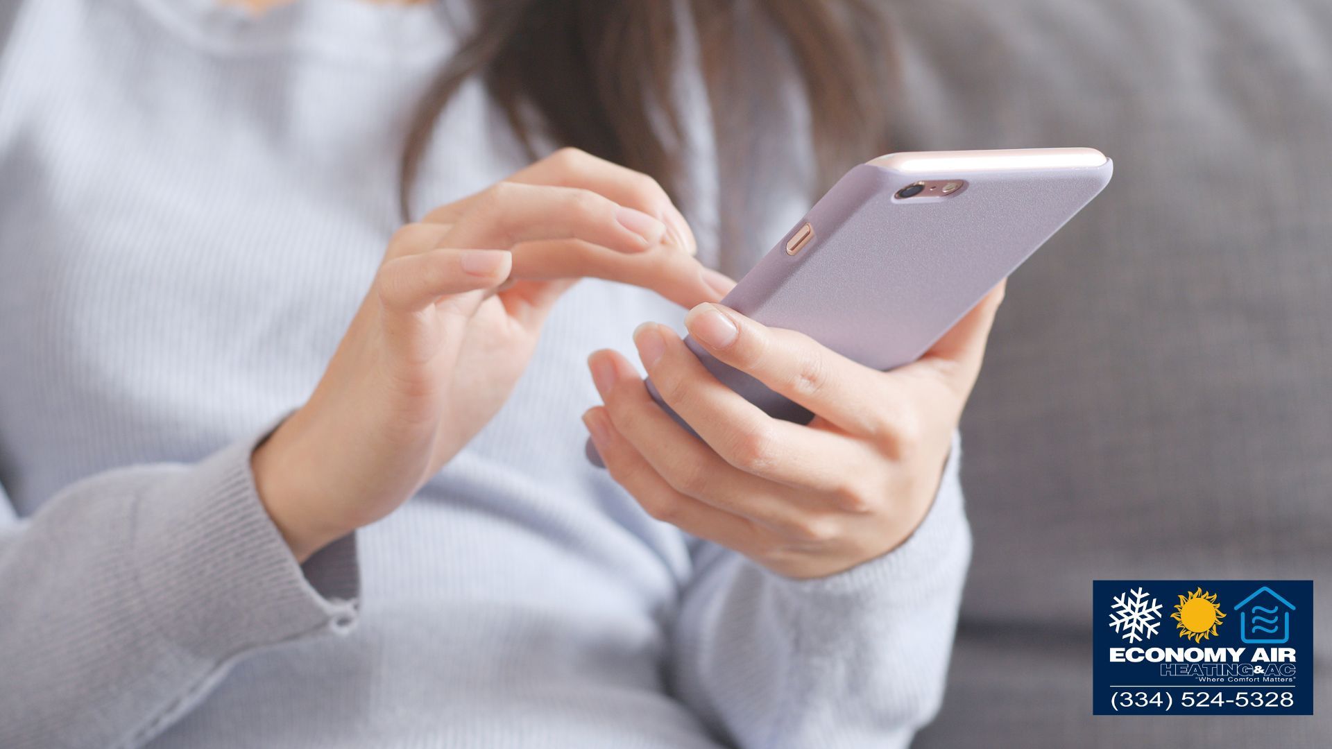 A woman is sitting on a couch using a cell phone.