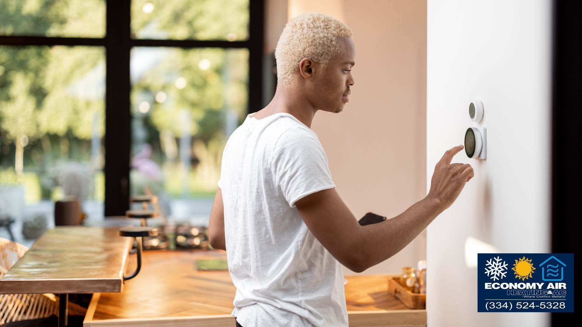 A man is adjusting a thermostat in a kitchen.