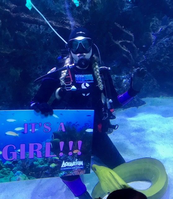 A woman in a red jumpsuit is standing in front of an aquarium