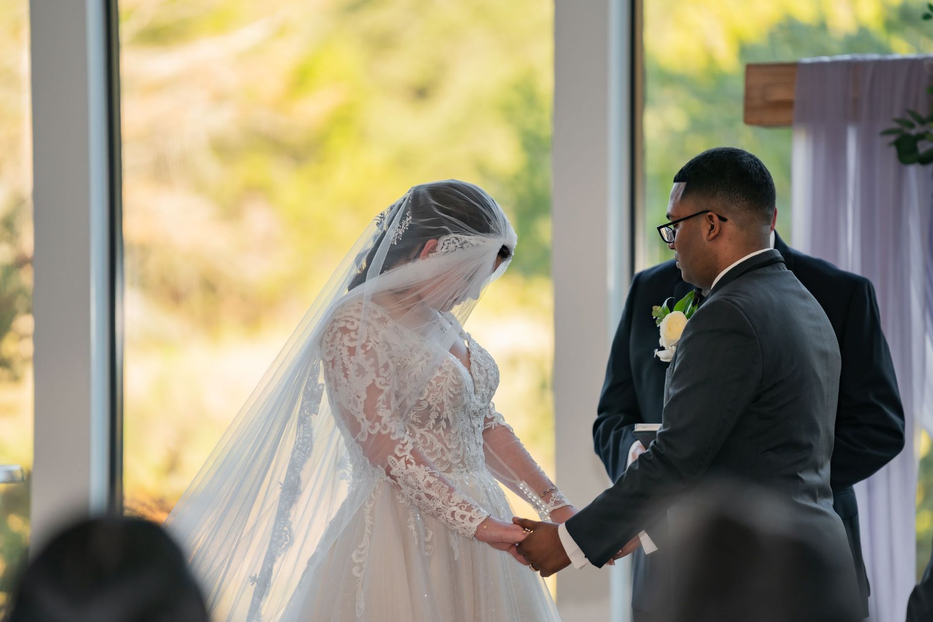 Bride and groom holding hands during a wedding ceremony under a pavilion