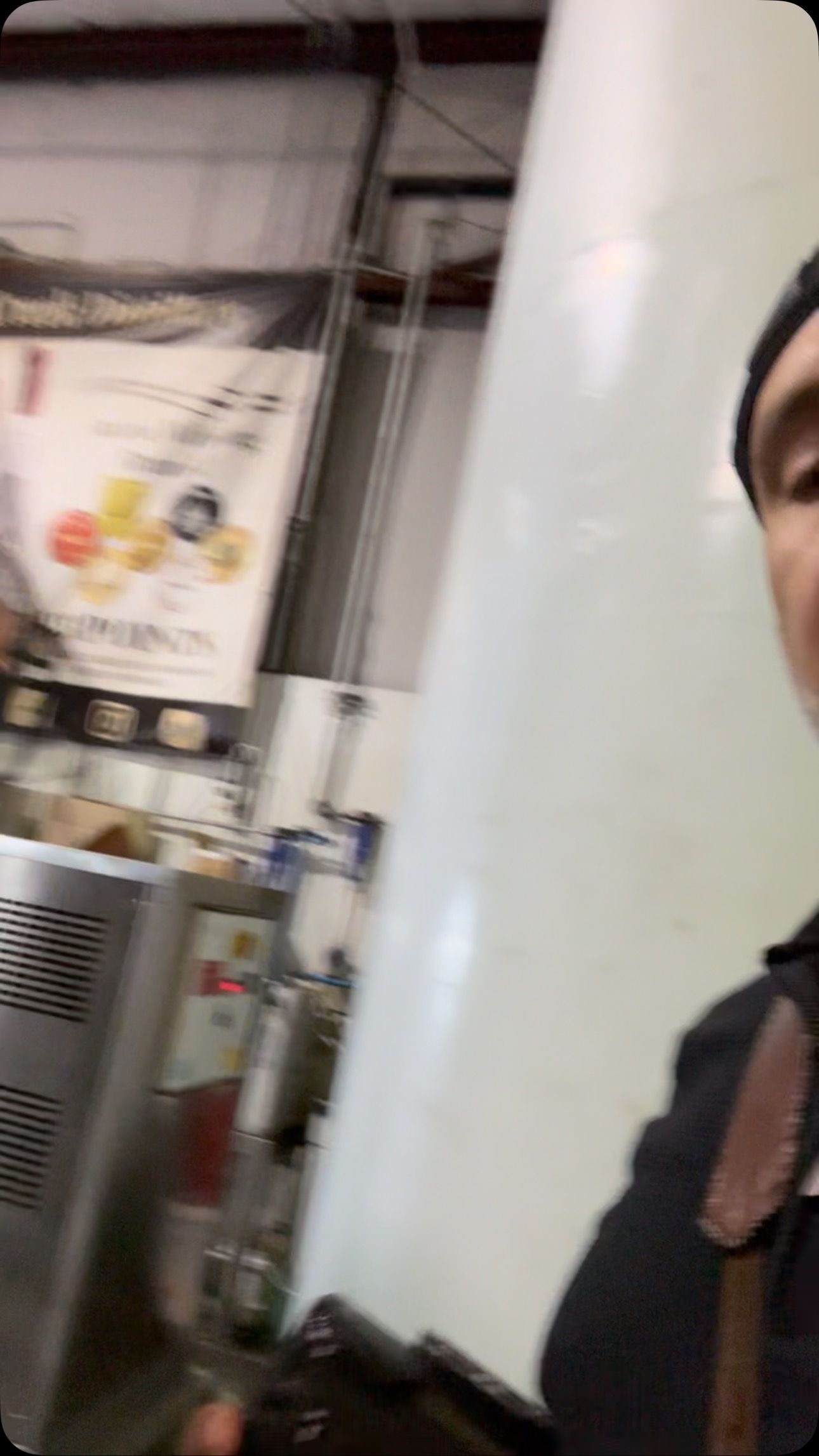Industrial interior with a poster, metal equipment, and part of a person in a dark jacket at right.