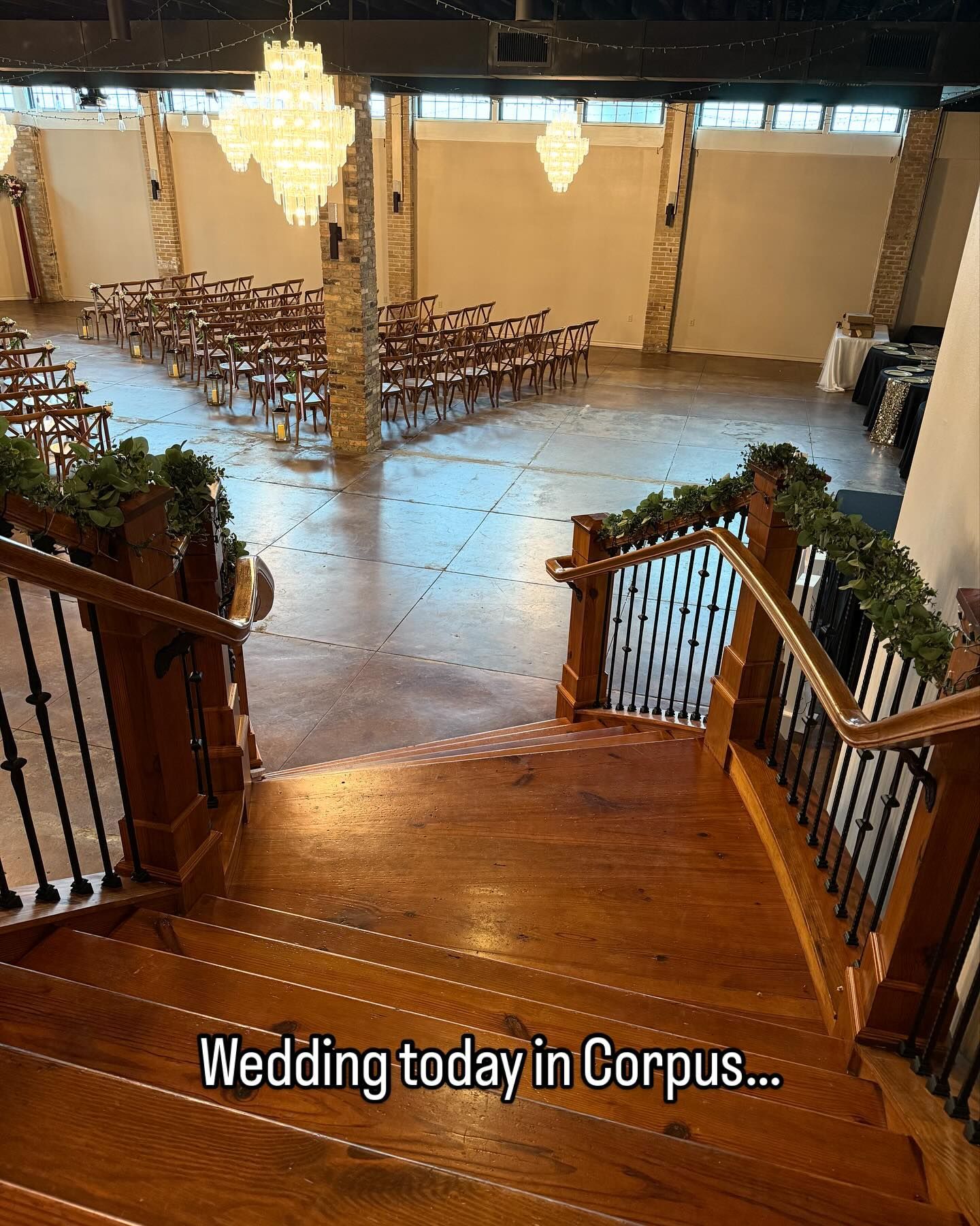 Wedding venue interior with rows of chairs, chandelier, and staircase leading to the ceremony area