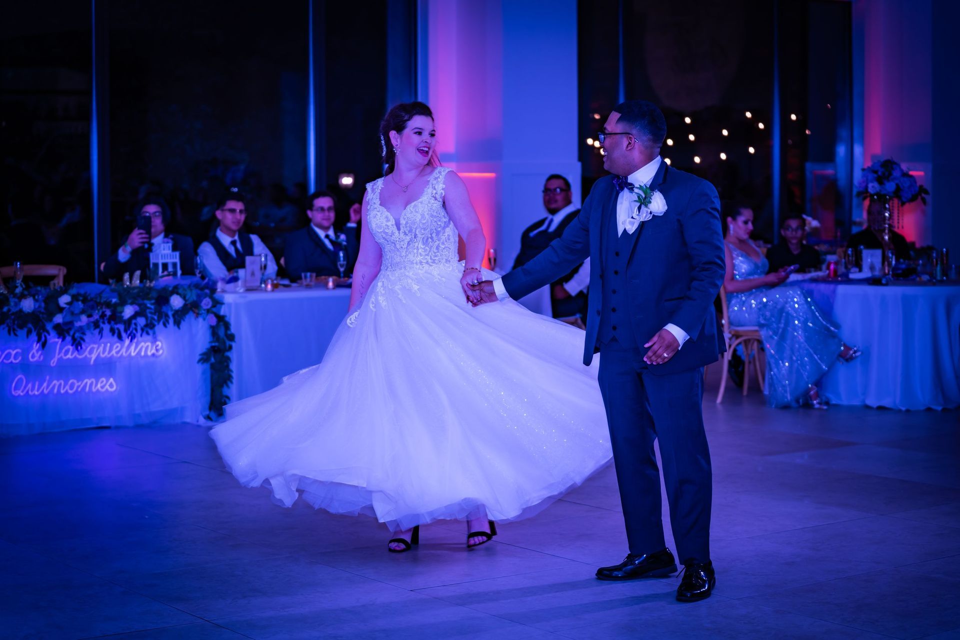 Bride and groom dancing at a reception under blue-purple lighting