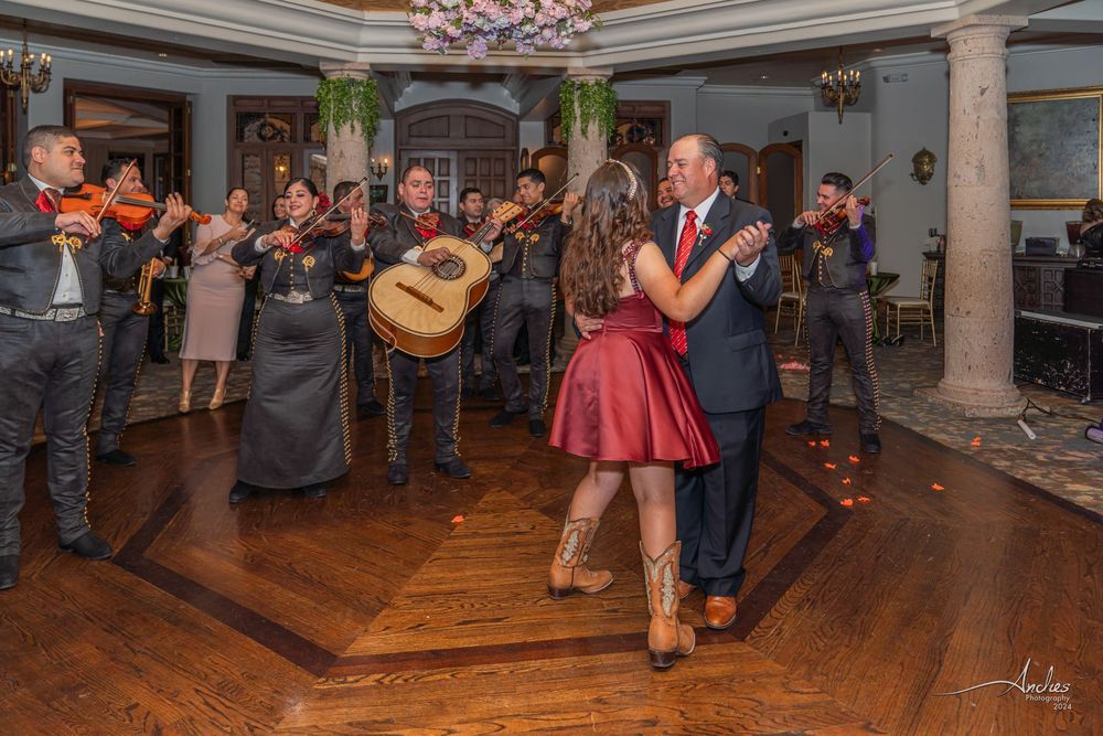 Couple dancing in a grand hall while musicians play guitars and violins nearby