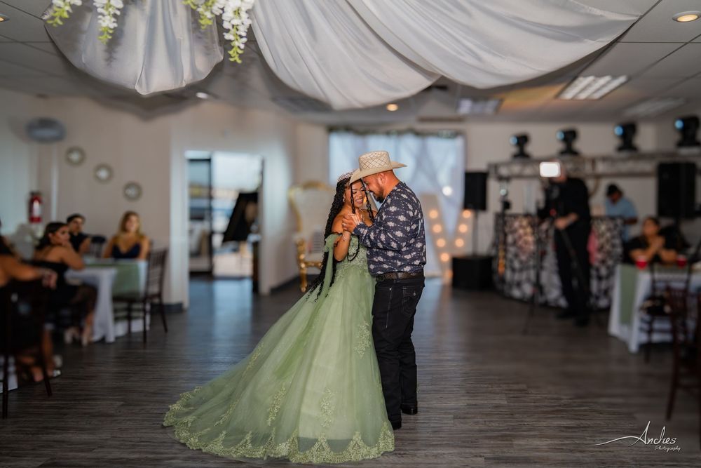 Couple slow dancing at a decorated indoor reception, with the bride in a green gown and the groom in dark attire.