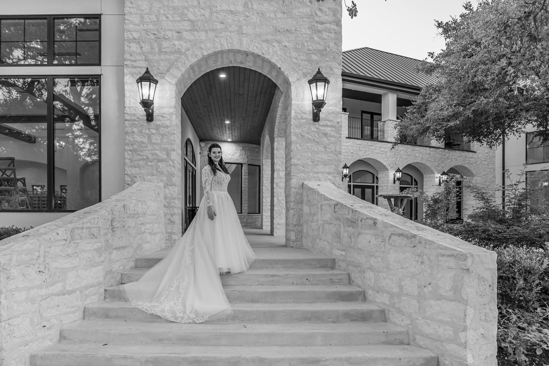 Bride in a white gown standing on stone steps outside a brick building