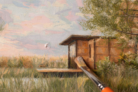 A brush painting a small wooden structure in a marshy landscape with tall grass and a colorful sky.