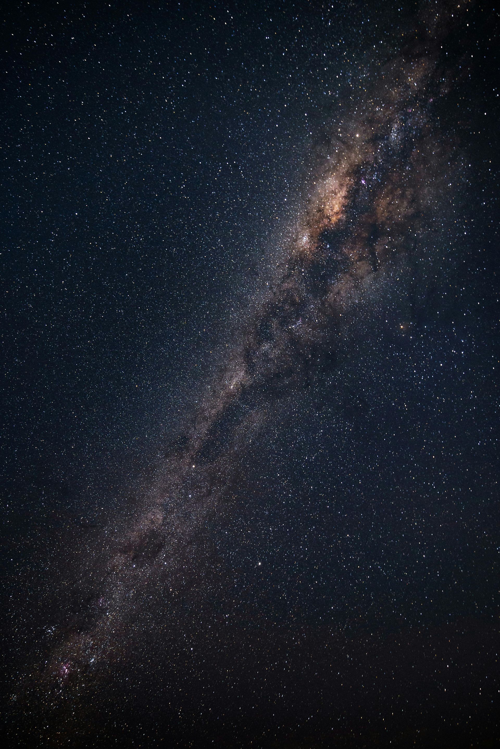 Milky Way galaxy spanning a dark night sky, with countless stars and faint colors.