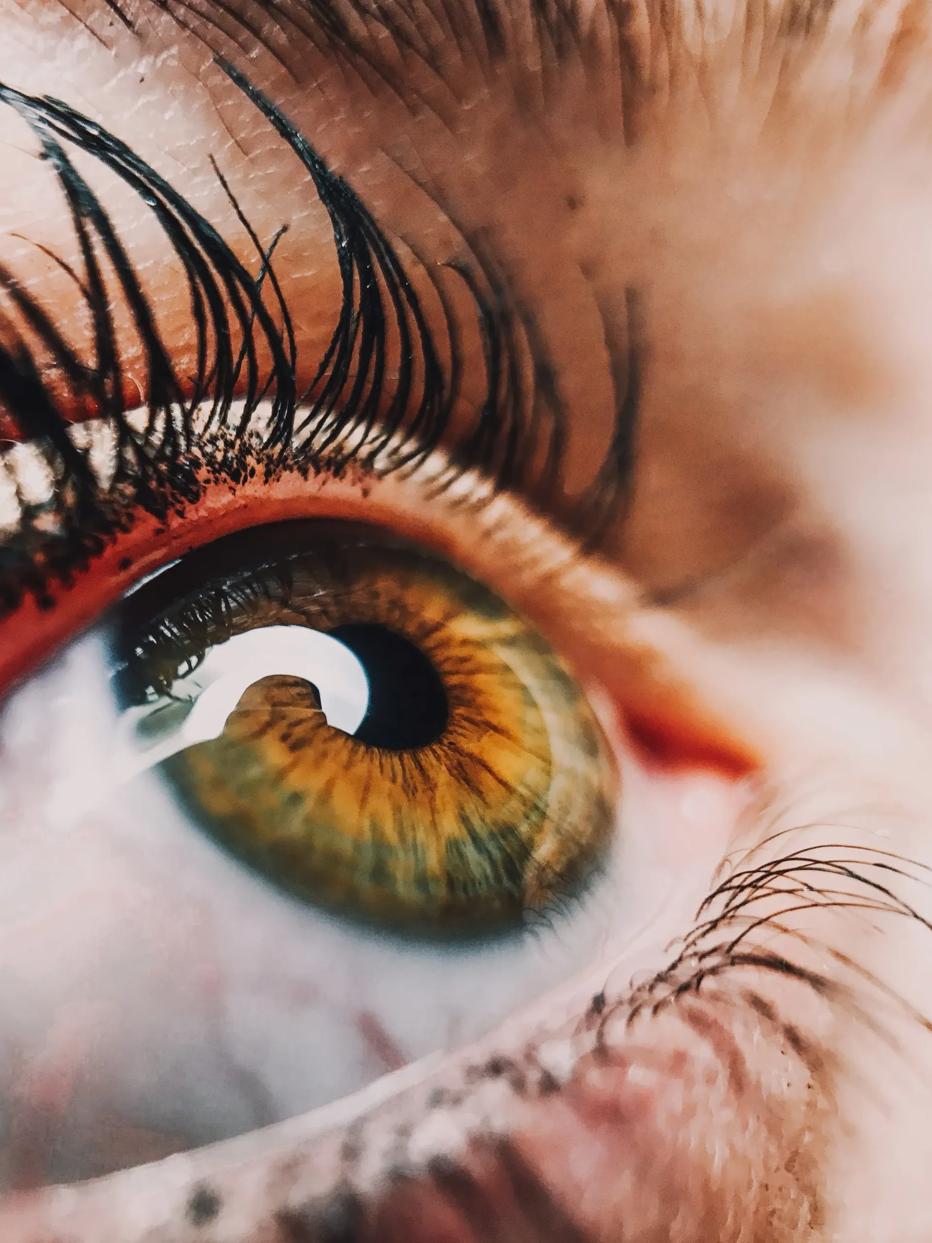 A close up of a woman 's green eye with long eyelashes
