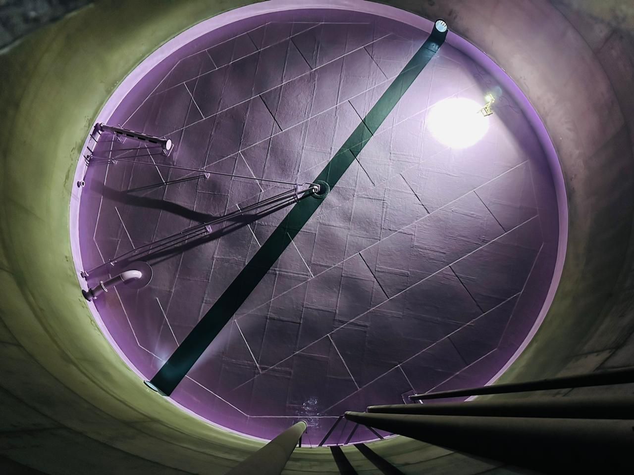 Túnel circular com tonalidade roxa, feixe diagonal e luz brilhante próximo ao canto superior direito.