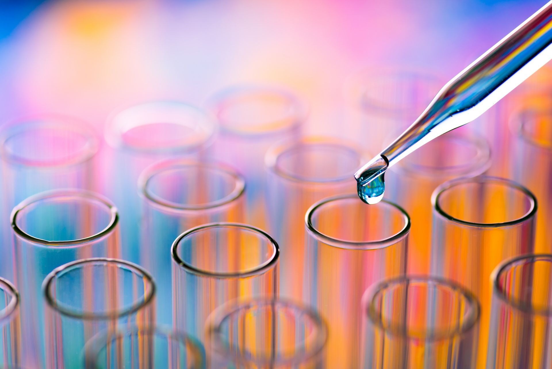 A pipette is dropping liquid into a test tube.
